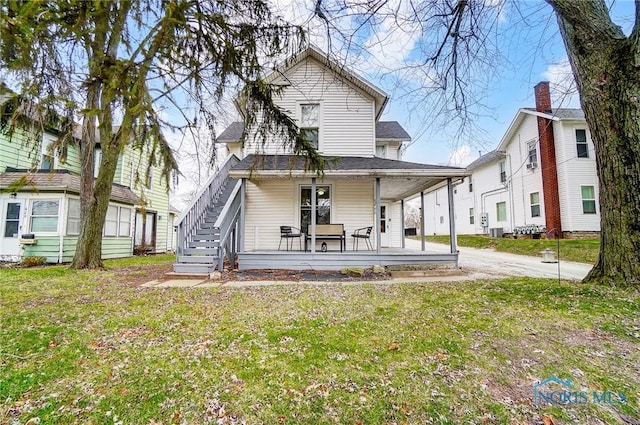 back of house with covered porch and a yard