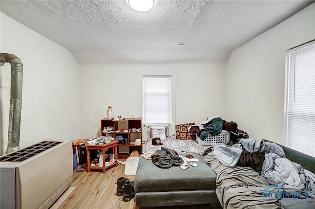 living room featuring heating unit, light hardwood / wood-style flooring, and a textured ceiling