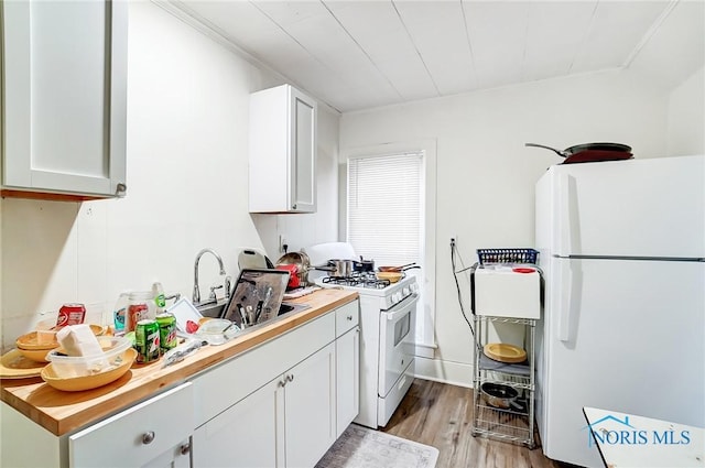 kitchen featuring sink, butcher block countertops, white appliances, white cabinets, and light wood-type flooring