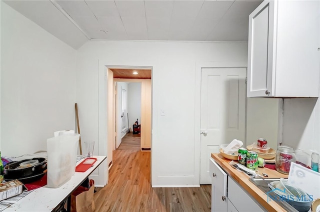 interior space with butcher block countertops, white cabinetry, and light hardwood / wood-style flooring