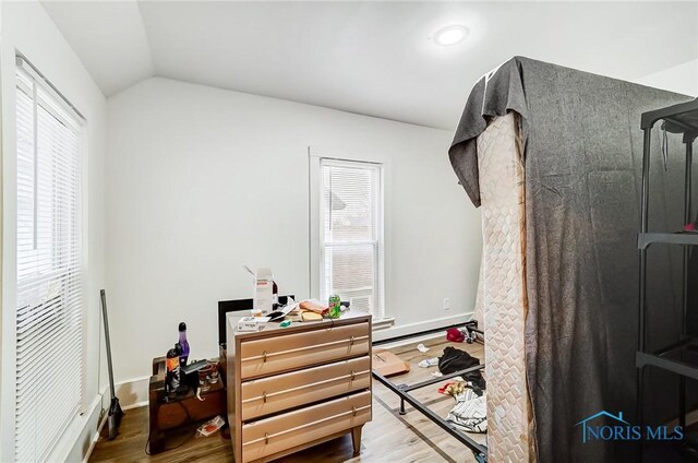 bedroom with multiple windows, hardwood / wood-style floors, a baseboard radiator, and lofted ceiling