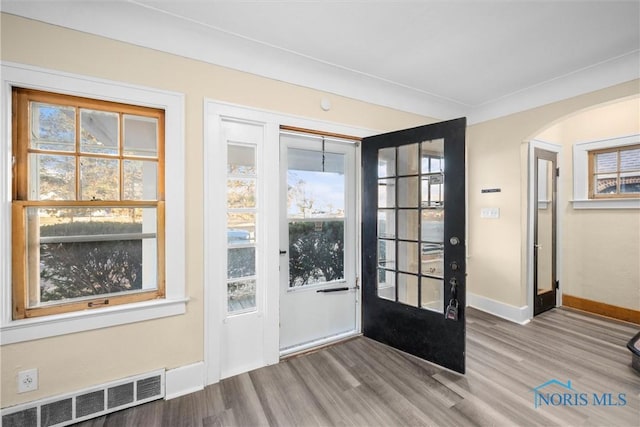 doorway with plenty of natural light, light hardwood / wood-style floors, and ornamental molding