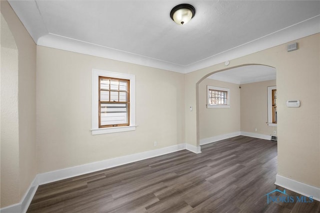 empty room with dark hardwood / wood-style flooring and crown molding