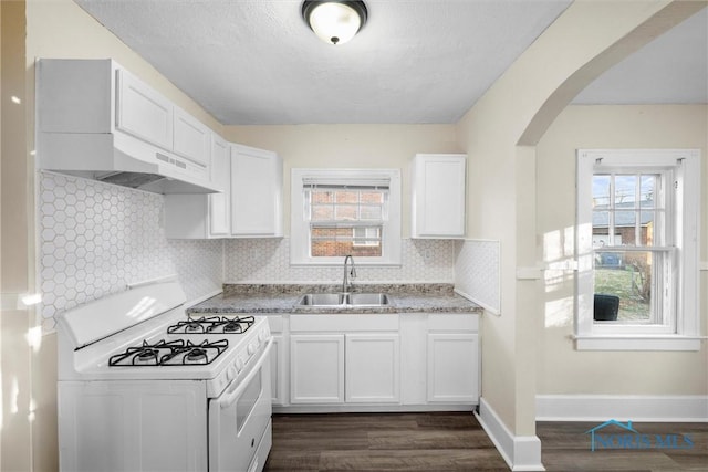 kitchen with tasteful backsplash, white cabinetry, white gas stove, and sink