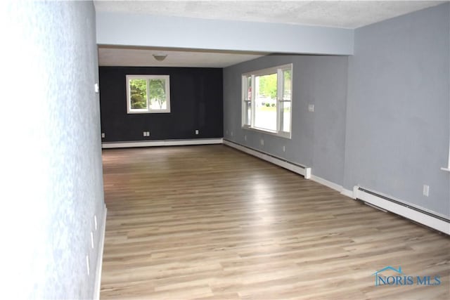 unfurnished room with light hardwood / wood-style floors, a textured ceiling, and a baseboard heating unit