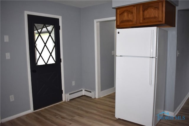 kitchen featuring light wood-type flooring, a baseboard heating unit, and white refrigerator