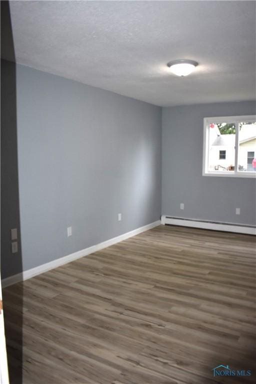 unfurnished room with baseboard heating and dark wood-type flooring