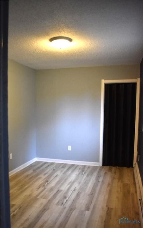 unfurnished room with hardwood / wood-style floors and a textured ceiling