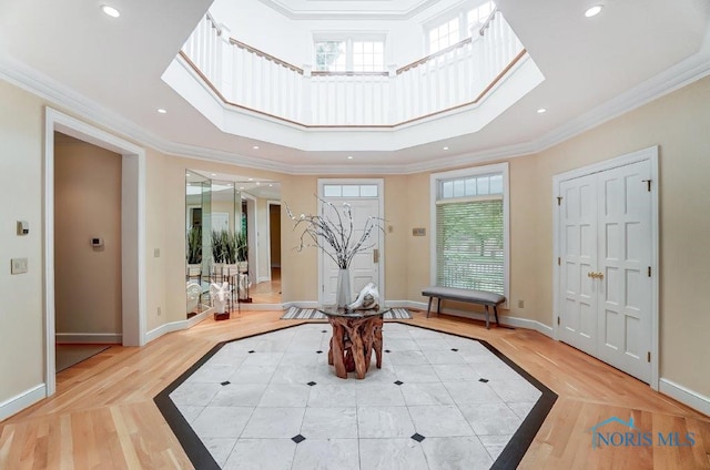 entryway featuring light hardwood / wood-style floors, crown molding, a high ceiling, and a skylight