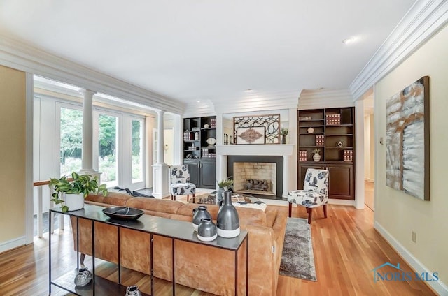 living room with ornate columns, crown molding, built in features, and light wood-type flooring