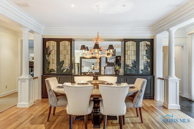 dining area with ornamental molding, light wood-type flooring, and an inviting chandelier