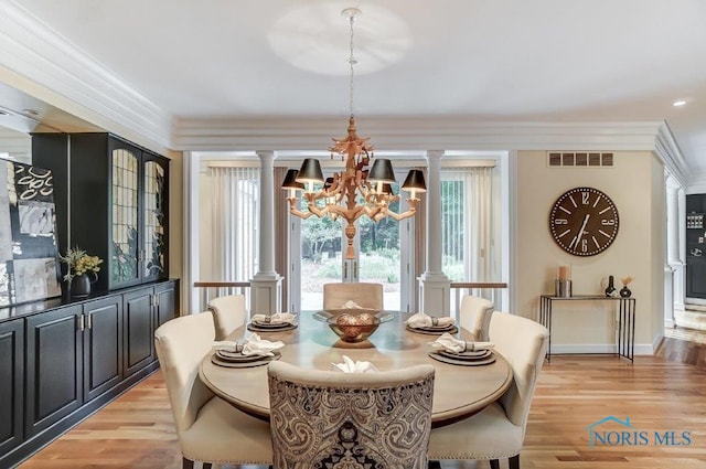 dining room featuring light hardwood / wood-style floors, decorative columns, crown molding, and a chandelier