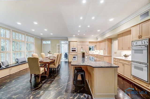 kitchen with a kitchen island with sink, black electric stovetop, paneled refrigerator, light stone countertops, and double oven