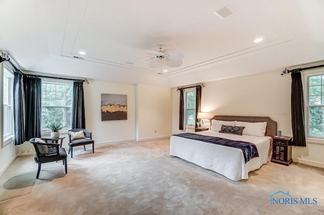 bedroom featuring ceiling fan, light carpet, and a tray ceiling