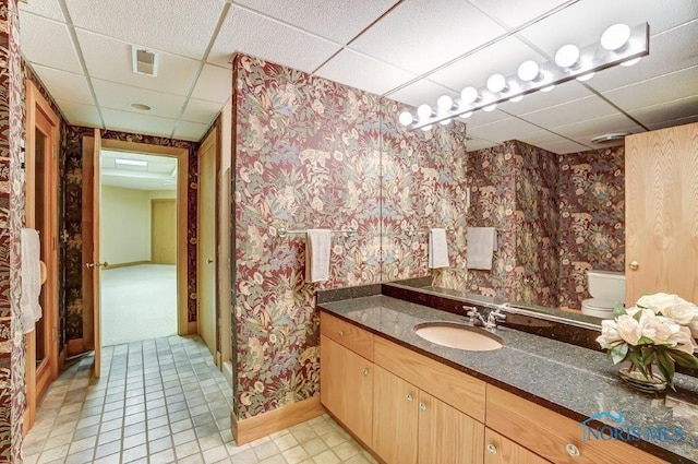 bathroom featuring a paneled ceiling, vanity, and toilet