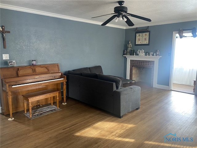 living room featuring hardwood / wood-style floors, ceiling fan, a fireplace, a textured ceiling, and crown molding