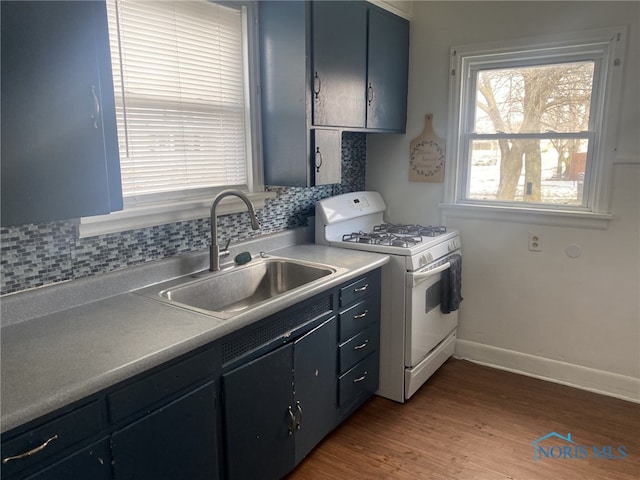 kitchen featuring hardwood / wood-style flooring, sink, backsplash, and white gas stove