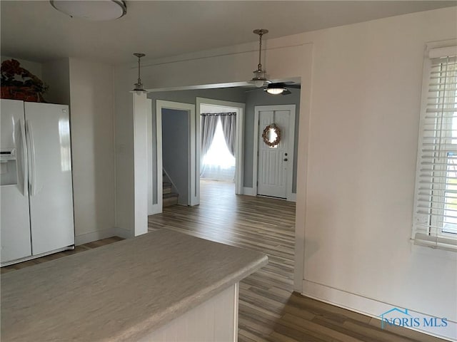 kitchen featuring ceiling fan, white fridge with ice dispenser, wood-type flooring, and decorative light fixtures