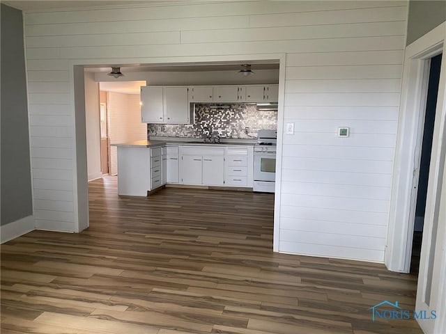 kitchen featuring dark hardwood / wood-style flooring, tasteful backsplash, white range oven, sink, and white cabinetry