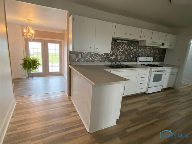 kitchen featuring white gas range, white cabinetry, french doors, sink, and decorative light fixtures