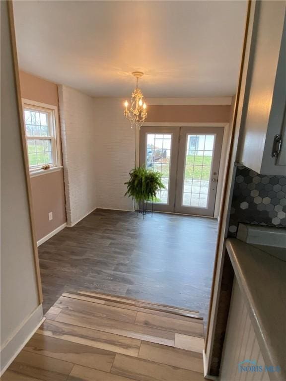 interior space featuring ornamental molding, an inviting chandelier, french doors, and dark wood-type flooring