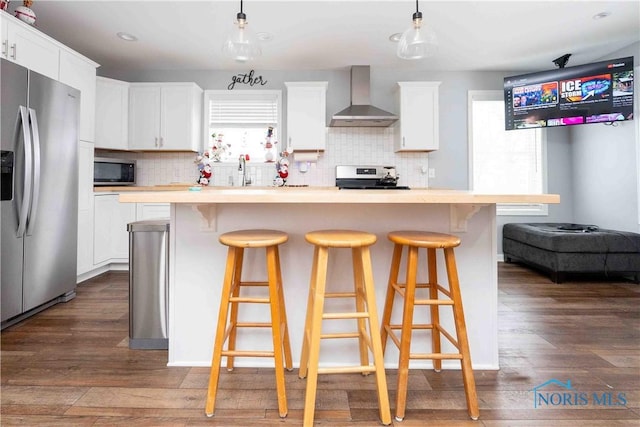 kitchen featuring dark wood finished floors, white cabinetry, stainless steel appliances, and wall chimney exhaust hood