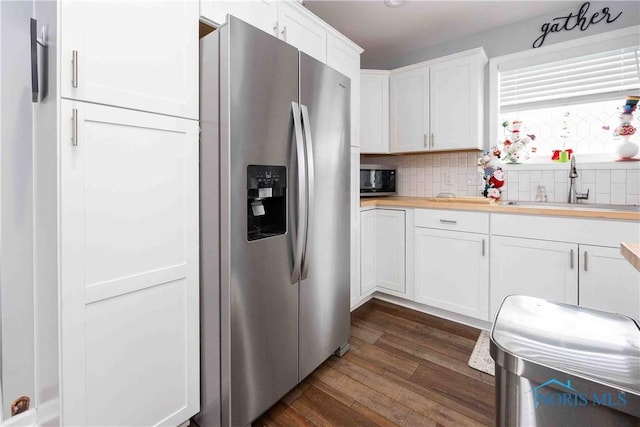 kitchen featuring dark wood-type flooring, a sink, white cabinetry, appliances with stainless steel finishes, and decorative backsplash