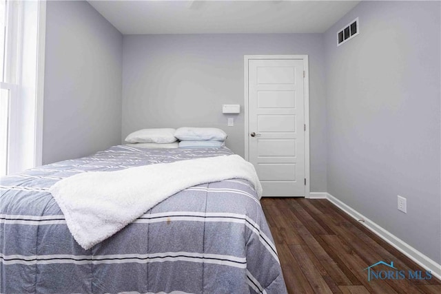 bedroom with visible vents, baseboards, and wood finished floors