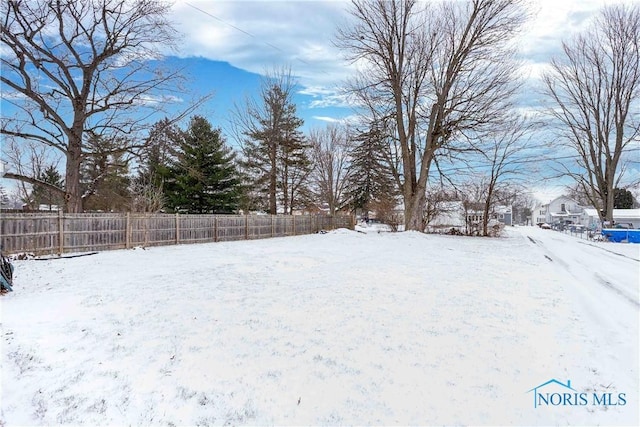 yard covered in snow featuring fence