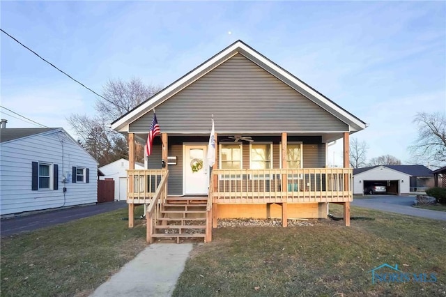 bungalow-style home with an outbuilding, covered porch, a detached garage, and a front yard