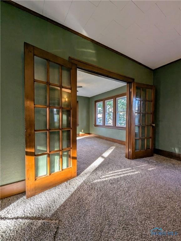 unfurnished room featuring crown molding and carpet floors