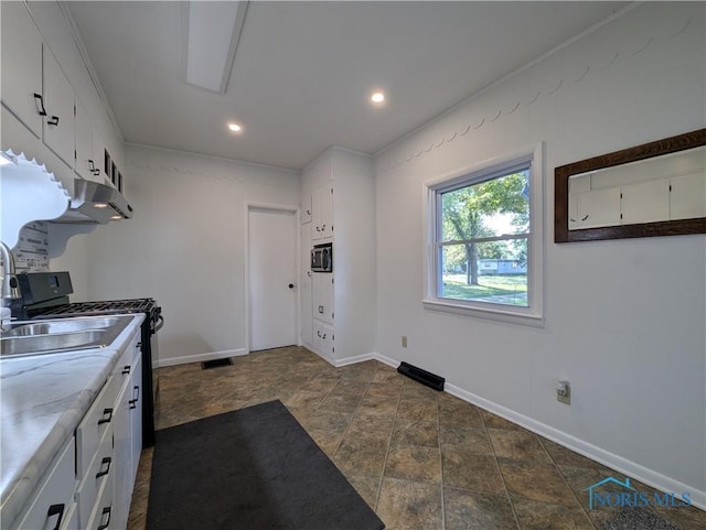 kitchen featuring gas stove, white cabinetry, and sink