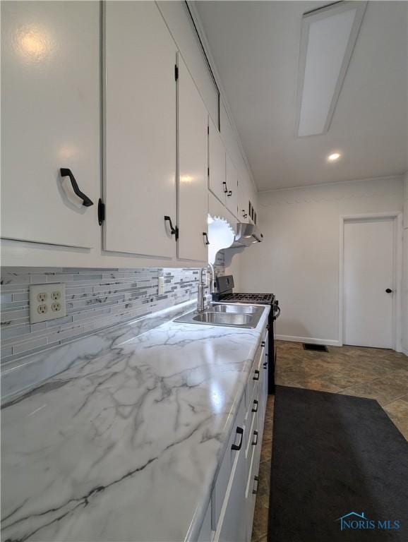 kitchen with white cabinets, decorative backsplash, and sink