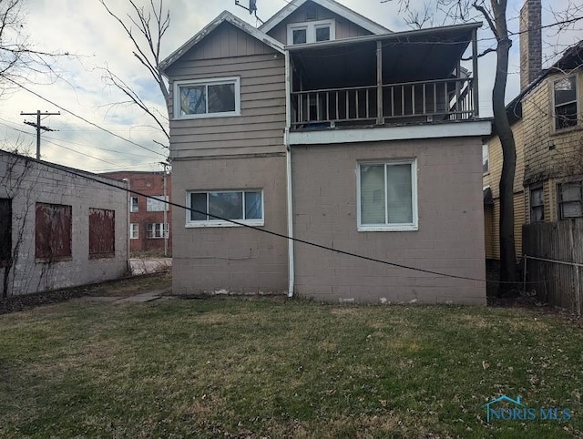 rear view of property featuring a yard and a balcony