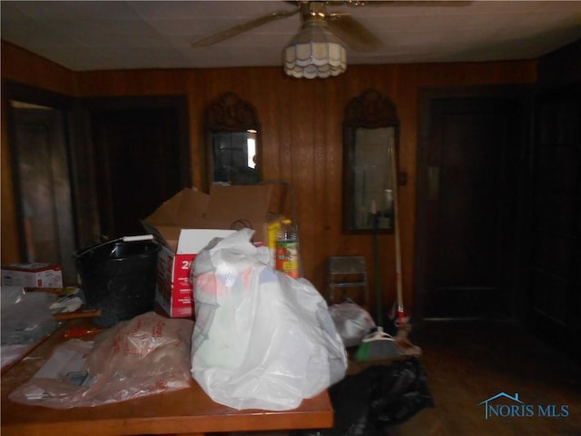 interior space with ceiling fan and wooden walls