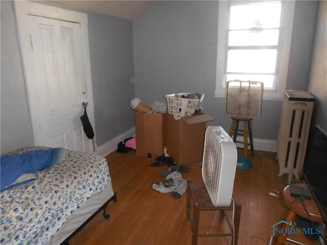 bedroom featuring radiator heating unit and hardwood / wood-style flooring