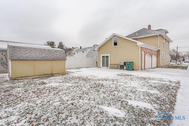 snow covered rear of property with a garage