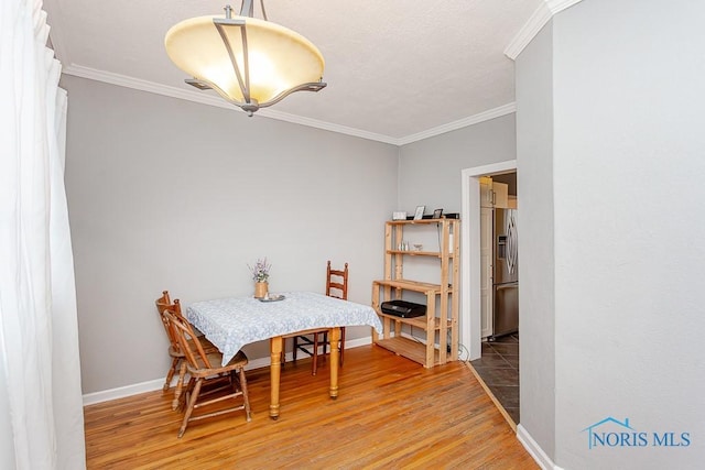 dining area with wood-type flooring and crown molding