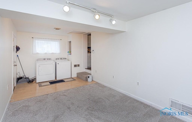 interior space featuring washing machine and dryer, rail lighting, and light colored carpet