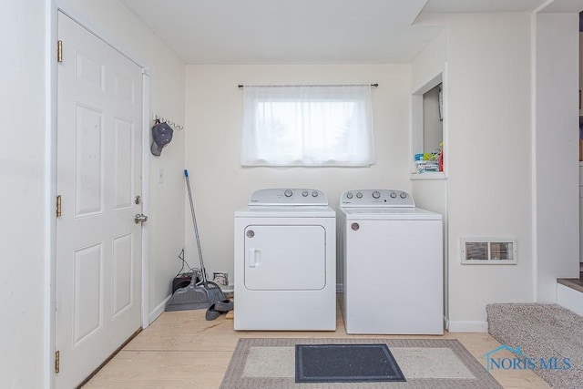 clothes washing area with washing machine and clothes dryer and light hardwood / wood-style floors