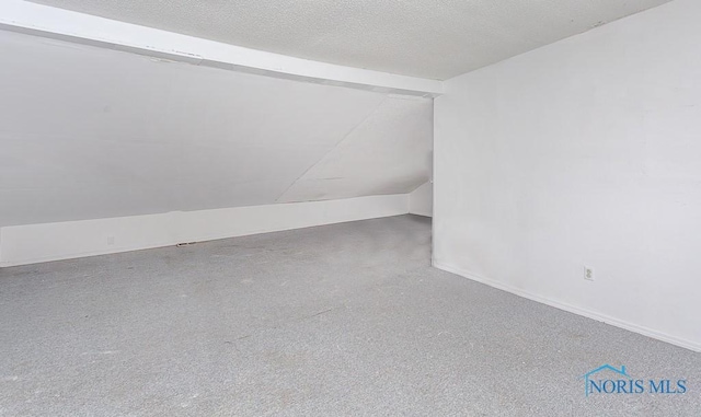 empty room with carpet floors, a textured ceiling, and lofted ceiling