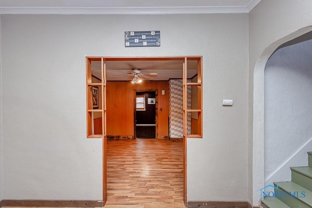 corridor with light hardwood / wood-style floors and ornamental molding