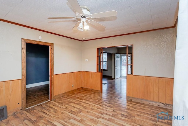 spare room with ceiling fan, crown molding, and light wood-type flooring