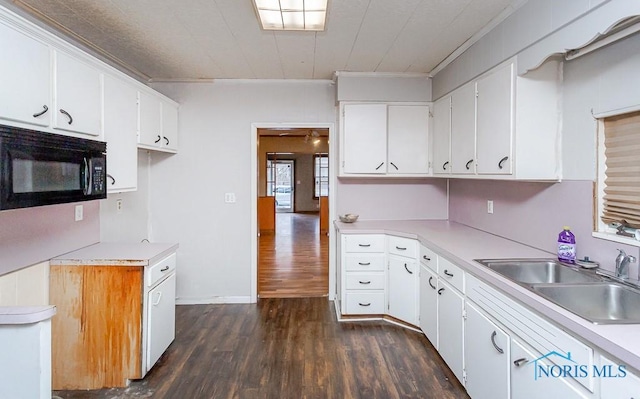 kitchen featuring dark hardwood / wood-style flooring, white cabinetry, ornamental molding, and sink