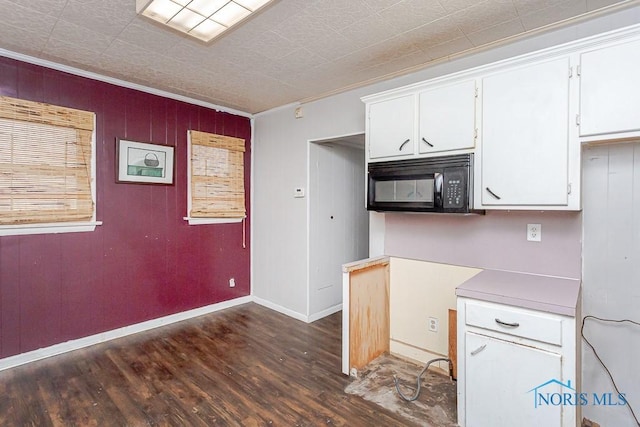 kitchen with wooden walls, dark hardwood / wood-style floors, white cabinetry, and crown molding