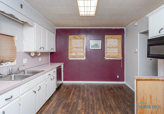 kitchen featuring dishwasher, wood walls, sink, ornamental molding, and white cabinetry