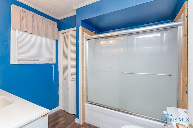 full bathroom featuring combined bath / shower with glass door, crown molding, wood-type flooring, toilet, and vanity