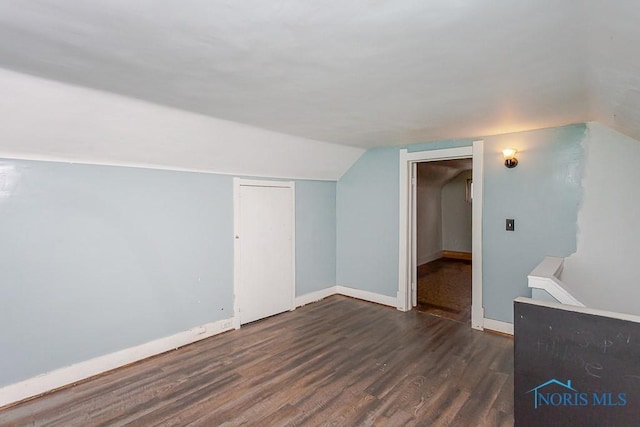 additional living space with vaulted ceiling and dark hardwood / wood-style floors