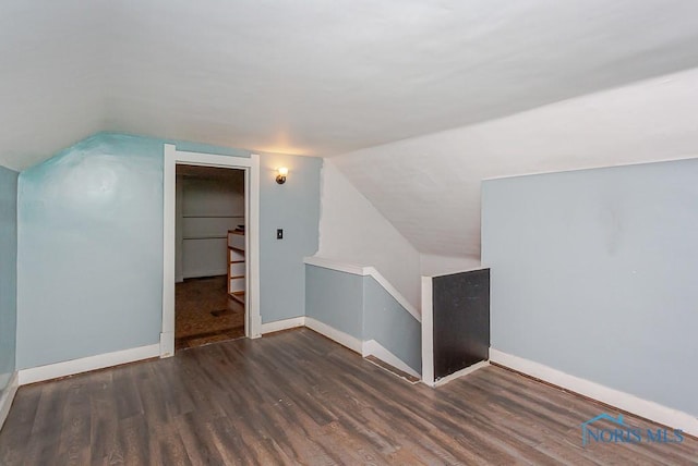 additional living space featuring dark wood-type flooring and lofted ceiling