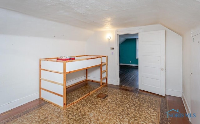 unfurnished bedroom with a textured ceiling and vaulted ceiling